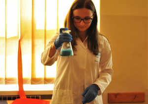 Zdjęcie przedstawia uczennicę wykonującą doświadczenie wykrywania białek metodą biuretową